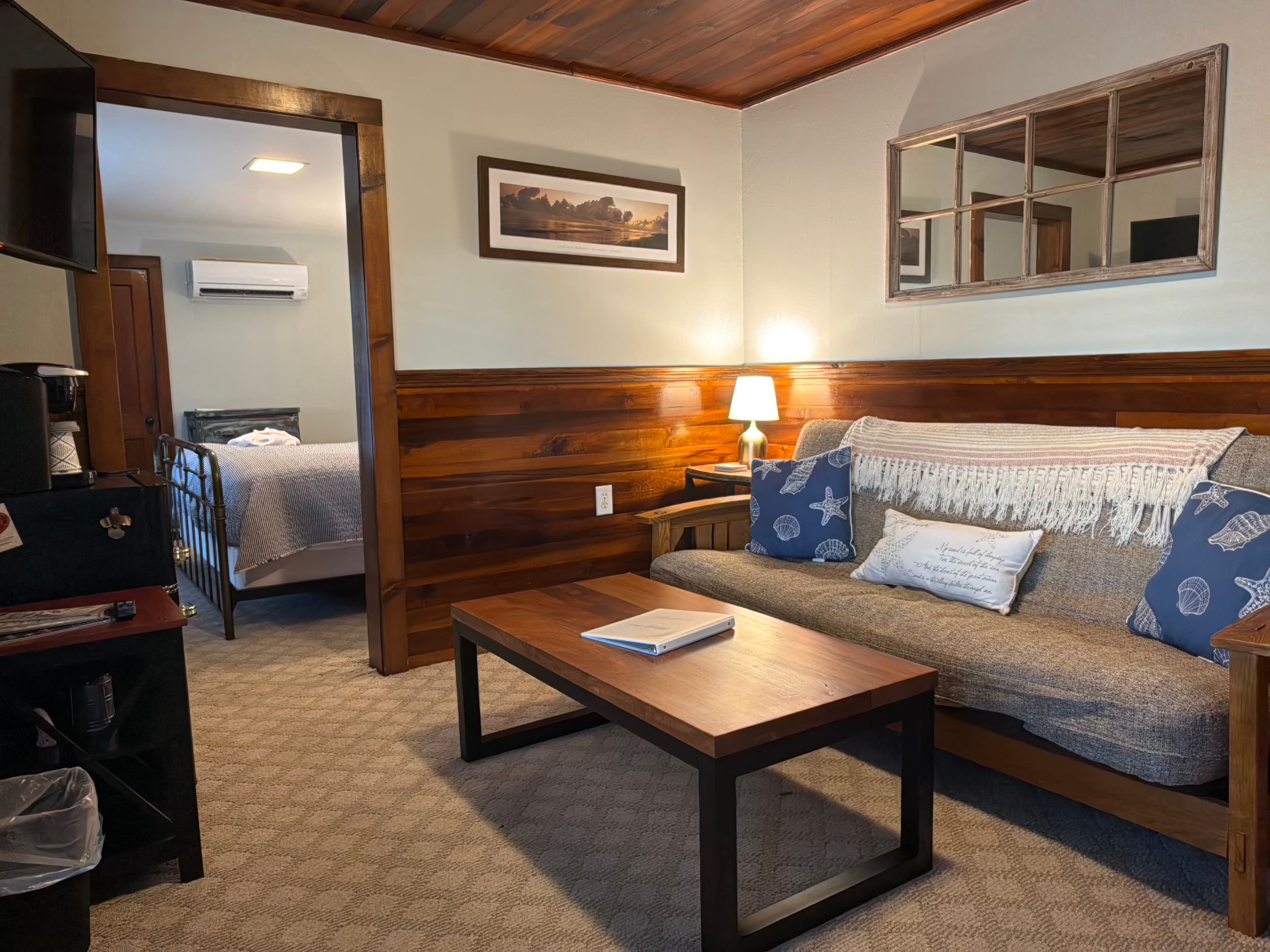 Cozy living area with a sofa, coffee table, and a view into a bedroom.
