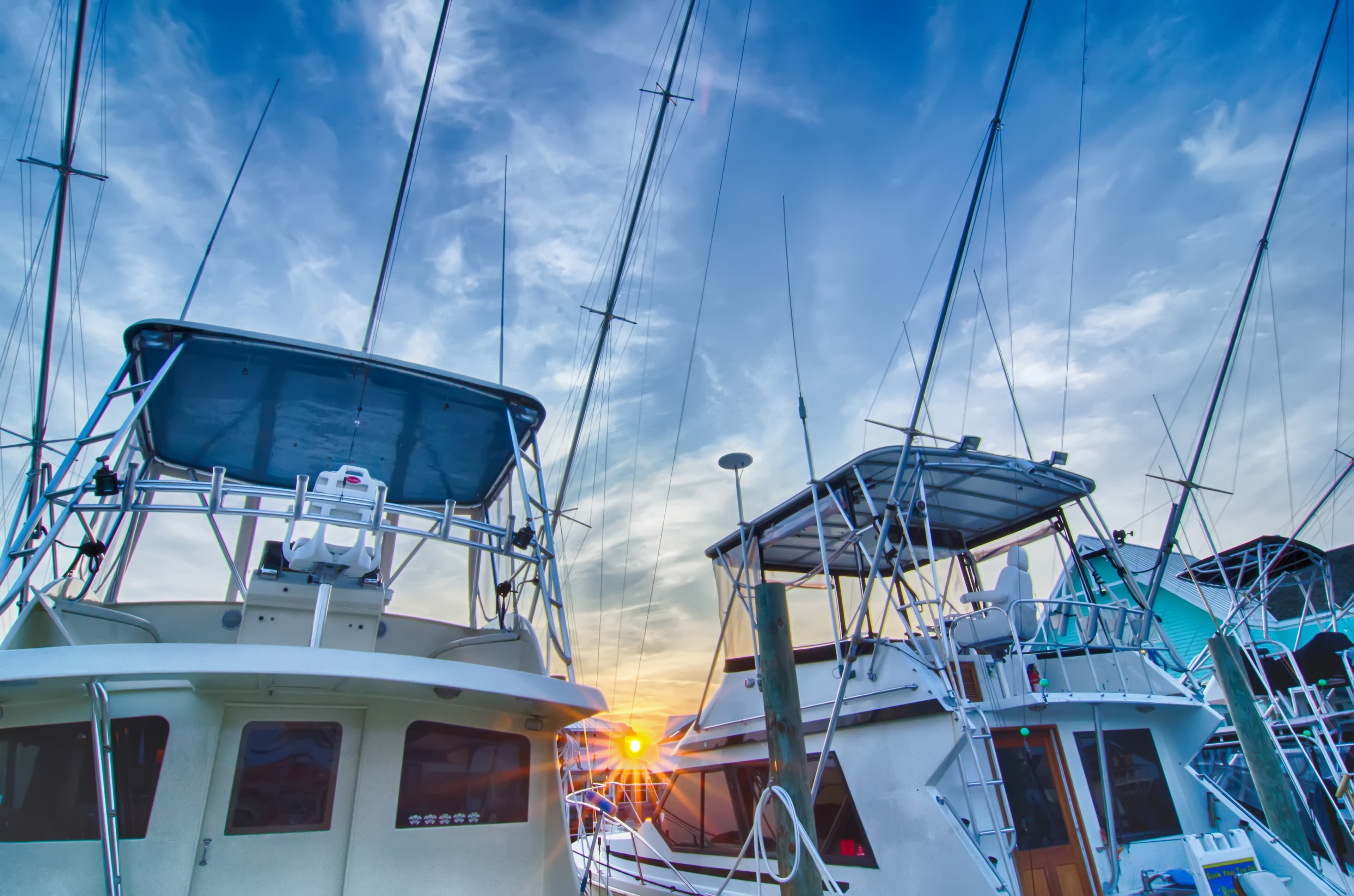 Two fishing boats at a marina with a sunset in the background.