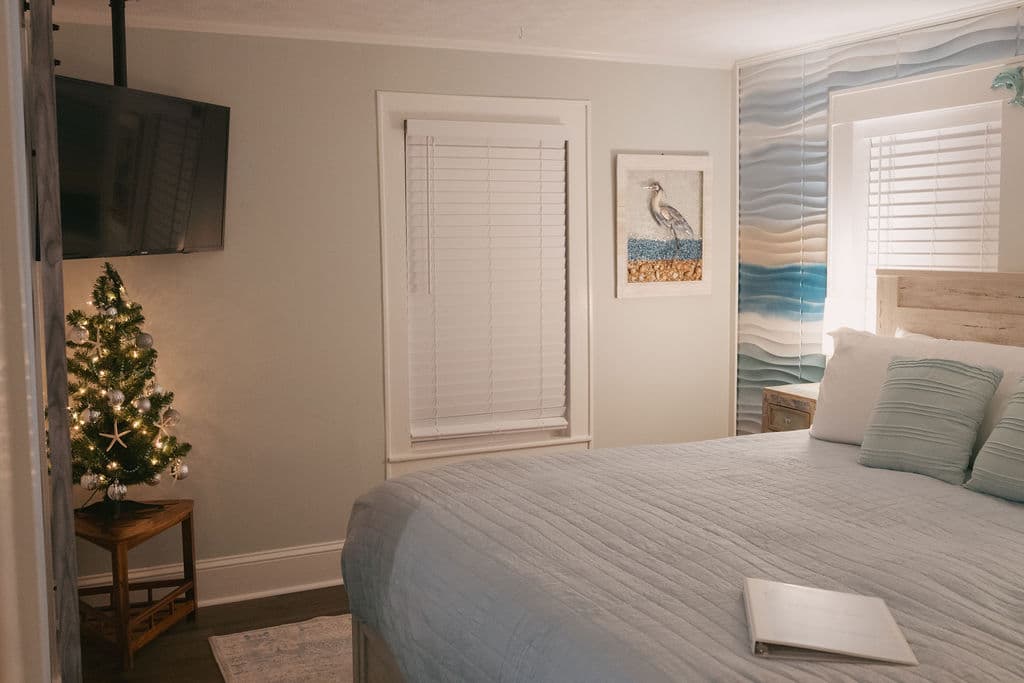 Cozy bedroom featuring a large bed, a small decorated Christmas tree, and seaside-themed decor.