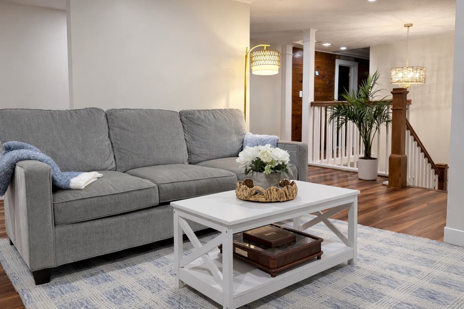 A cozy living room featuring a gray sofa, white coffee table, and decorative plants.