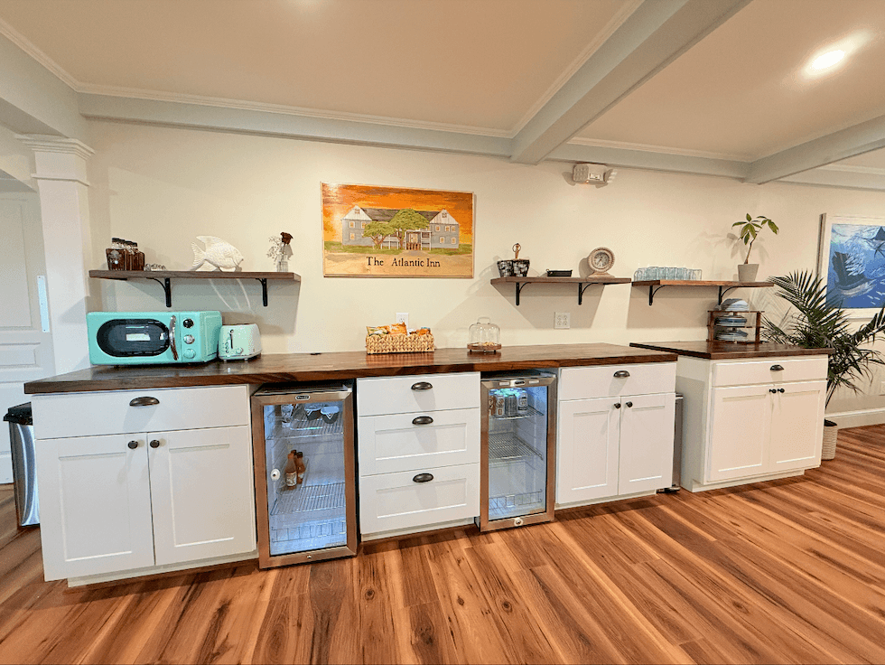 A modern kitchen counter with a wooden top, white cabinets, and small appliances, accented by a decorative painting on the wall.