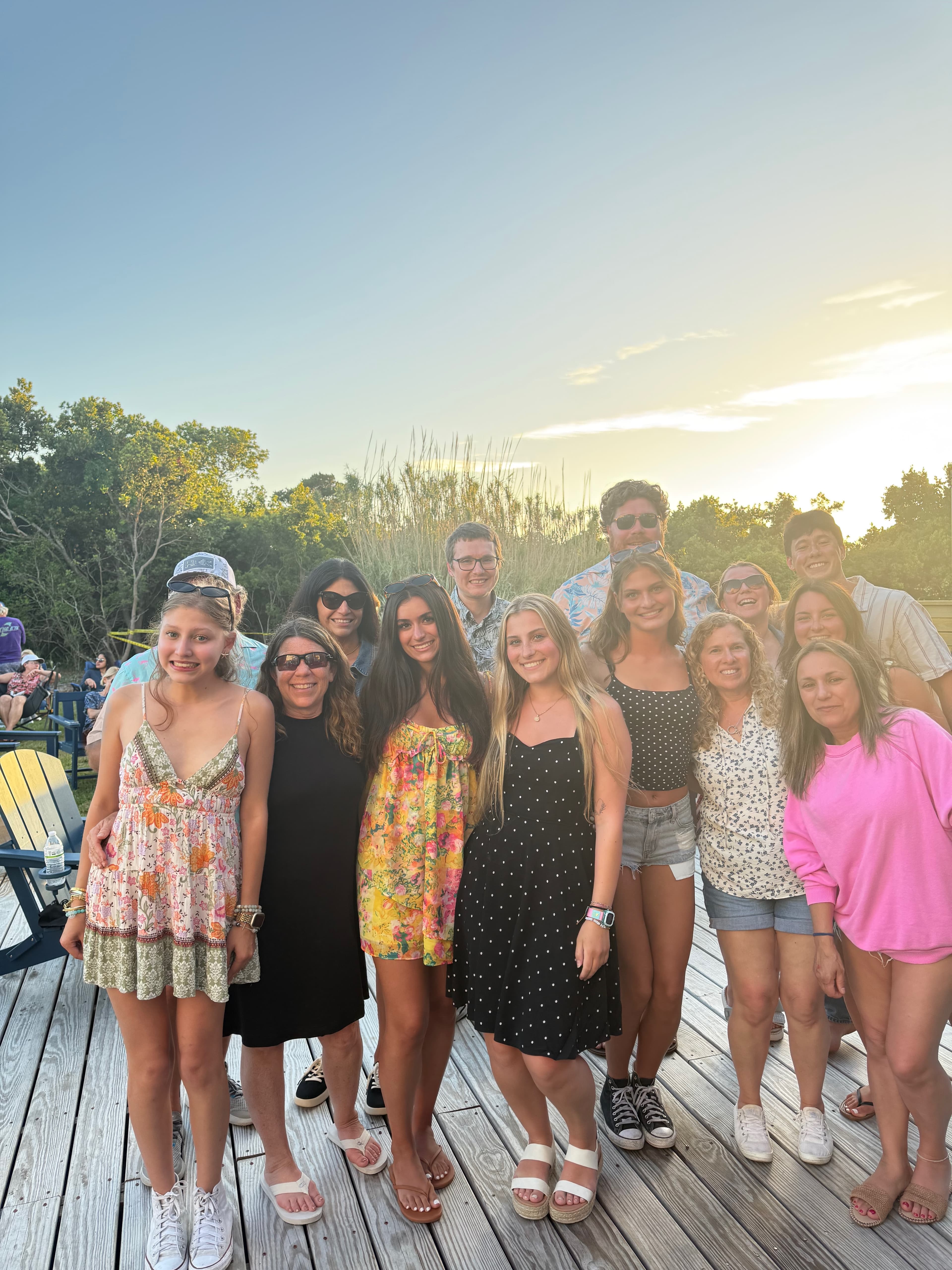 A large group of people posing together outdoors during sunset.