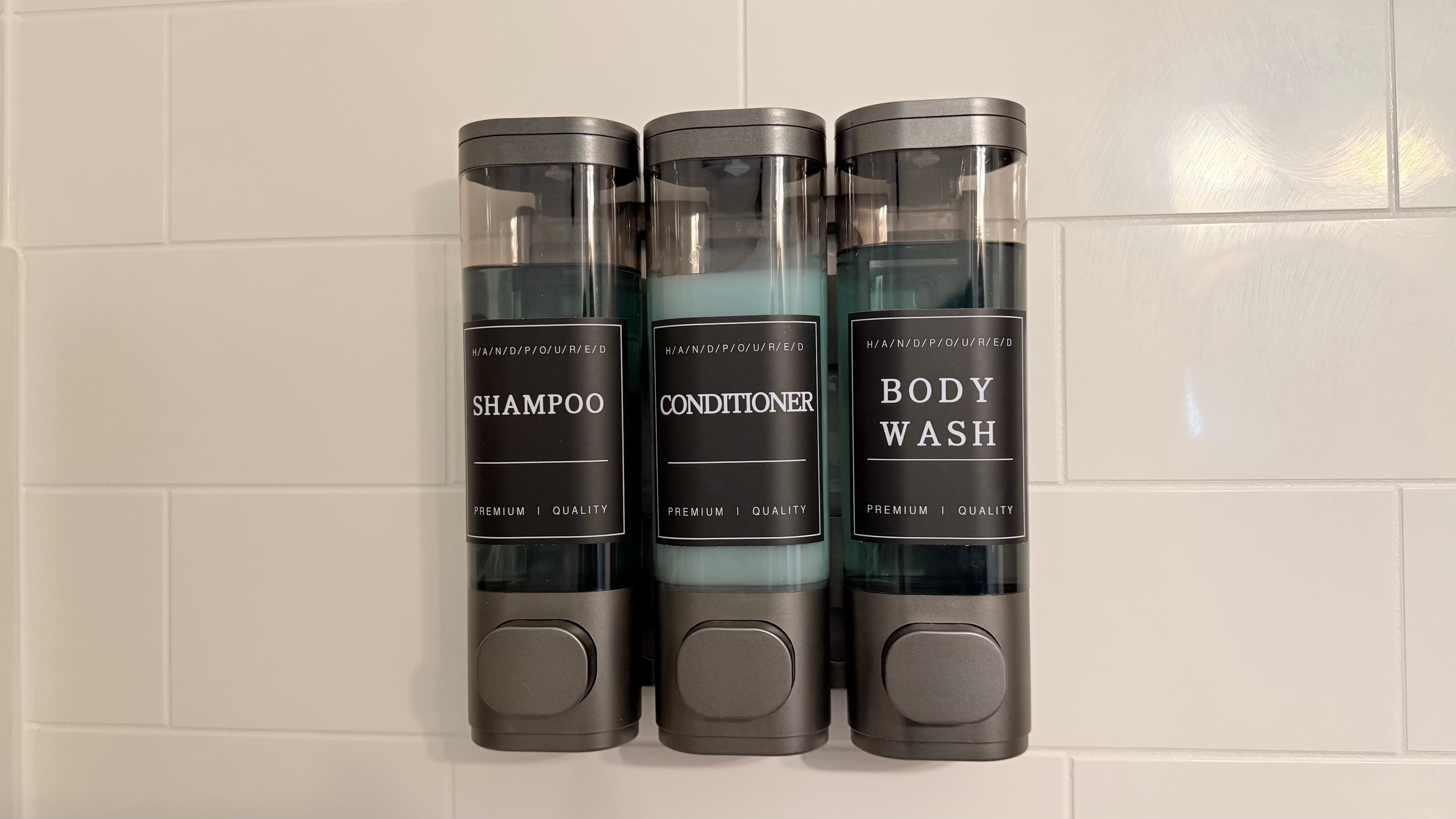 Three wall-mounted dispensers labeled "Shampoo," "Conditioner," and "Body Wash."