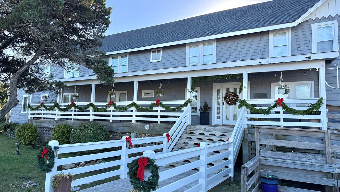 A decorated coastal building with a wide porch, festooned with holiday garlands and wreaths.