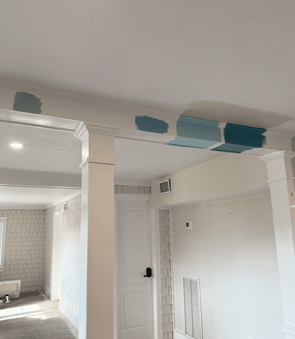 A ceiling with paint swatches in various shades of blue above a doorway in a room undergoing renovation.