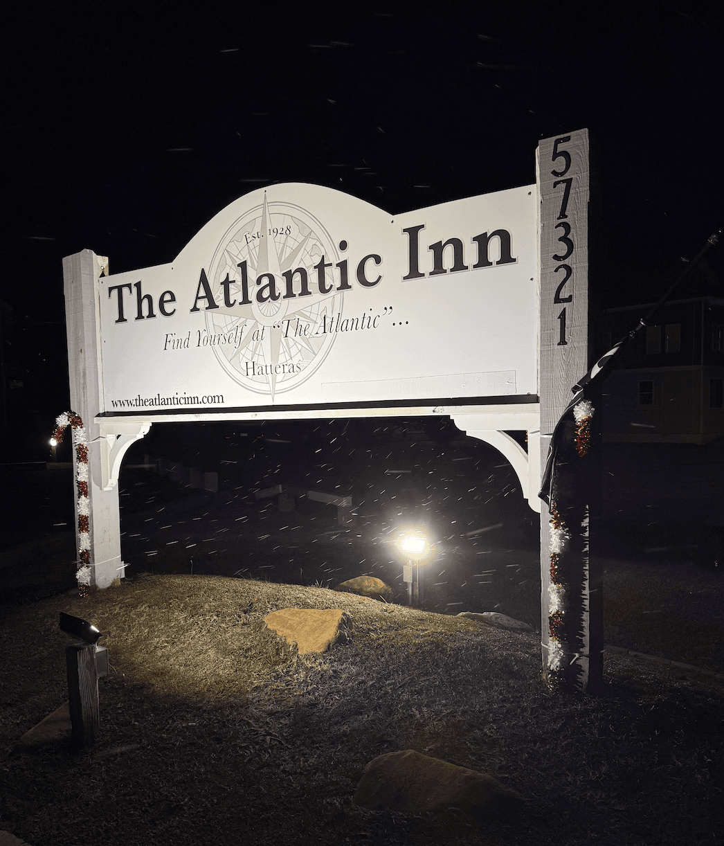 Illuminated sign for The Atlantic Inn in Hatteras, showing its name and website.