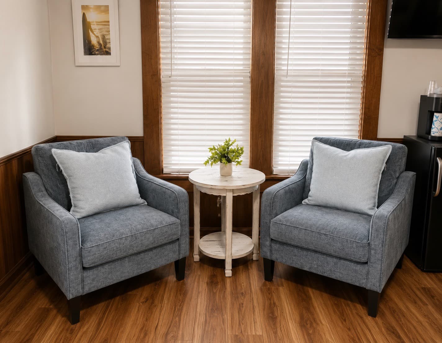 A cozy corner featuring two blue armchairs and a small round table with a floral arrangement.