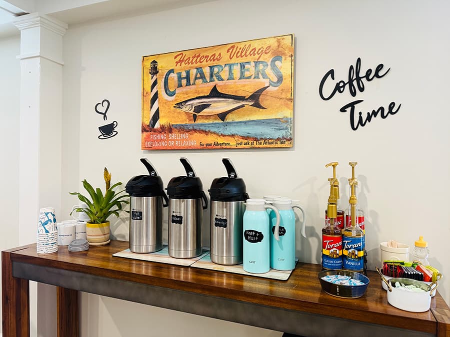 A coffee station with stainless steel dispensers, flavored syrups, and a decorative sign that reads "Coffee Time."