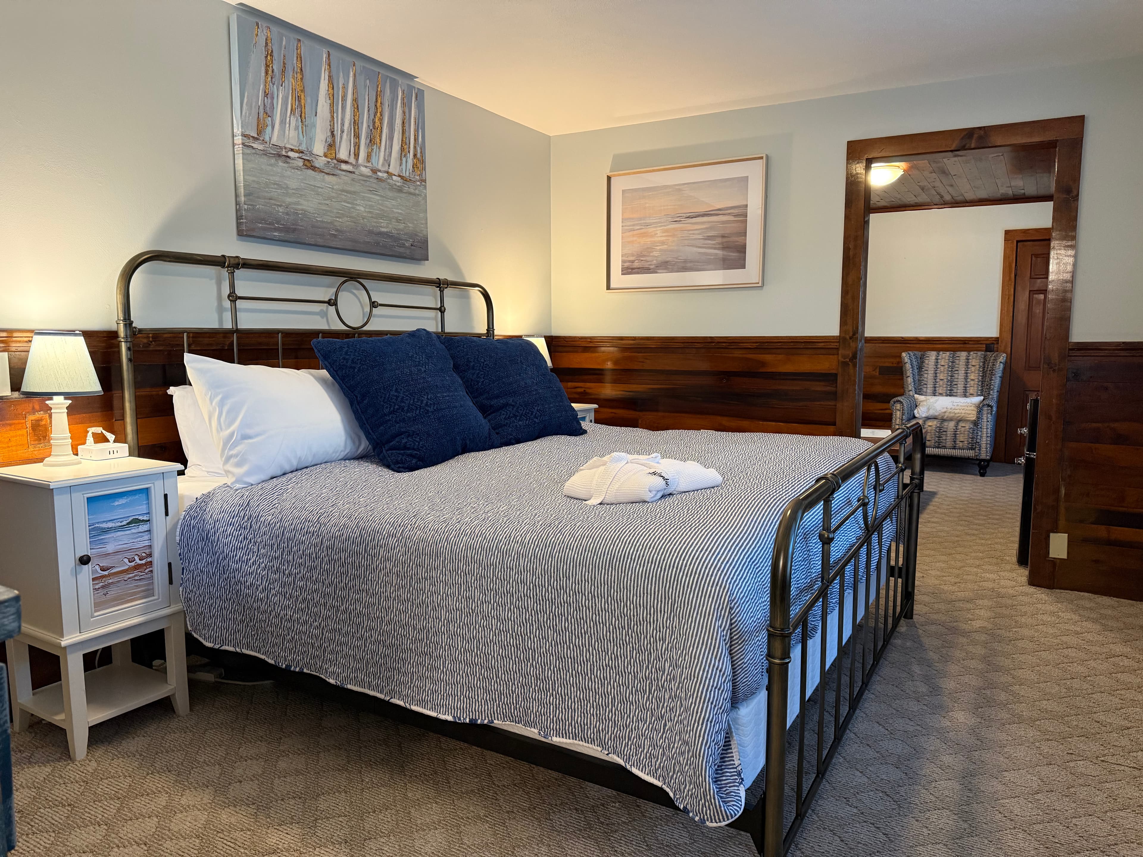 A cozy bedroom featuring a metal bed frame, blue accents, and nautical-themed artwork.
