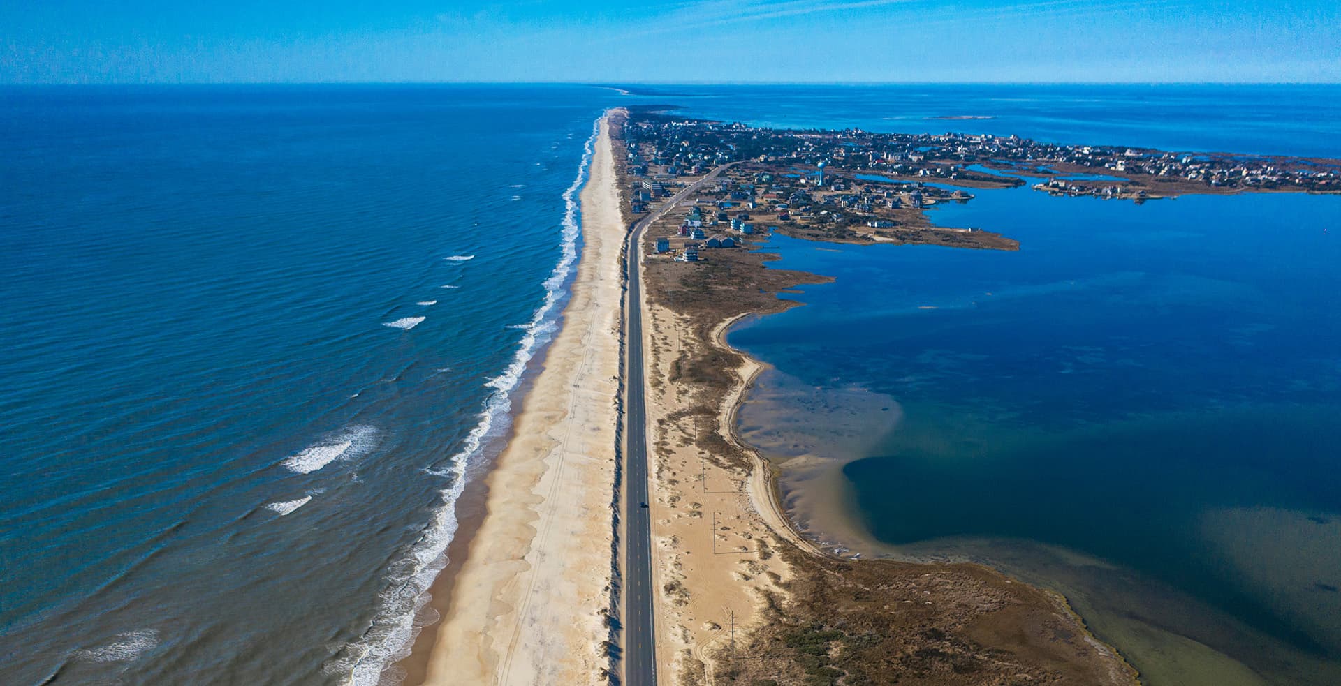 Aerial view of a coastline featuring a road alongside sandy beaches and a blue lagoon.