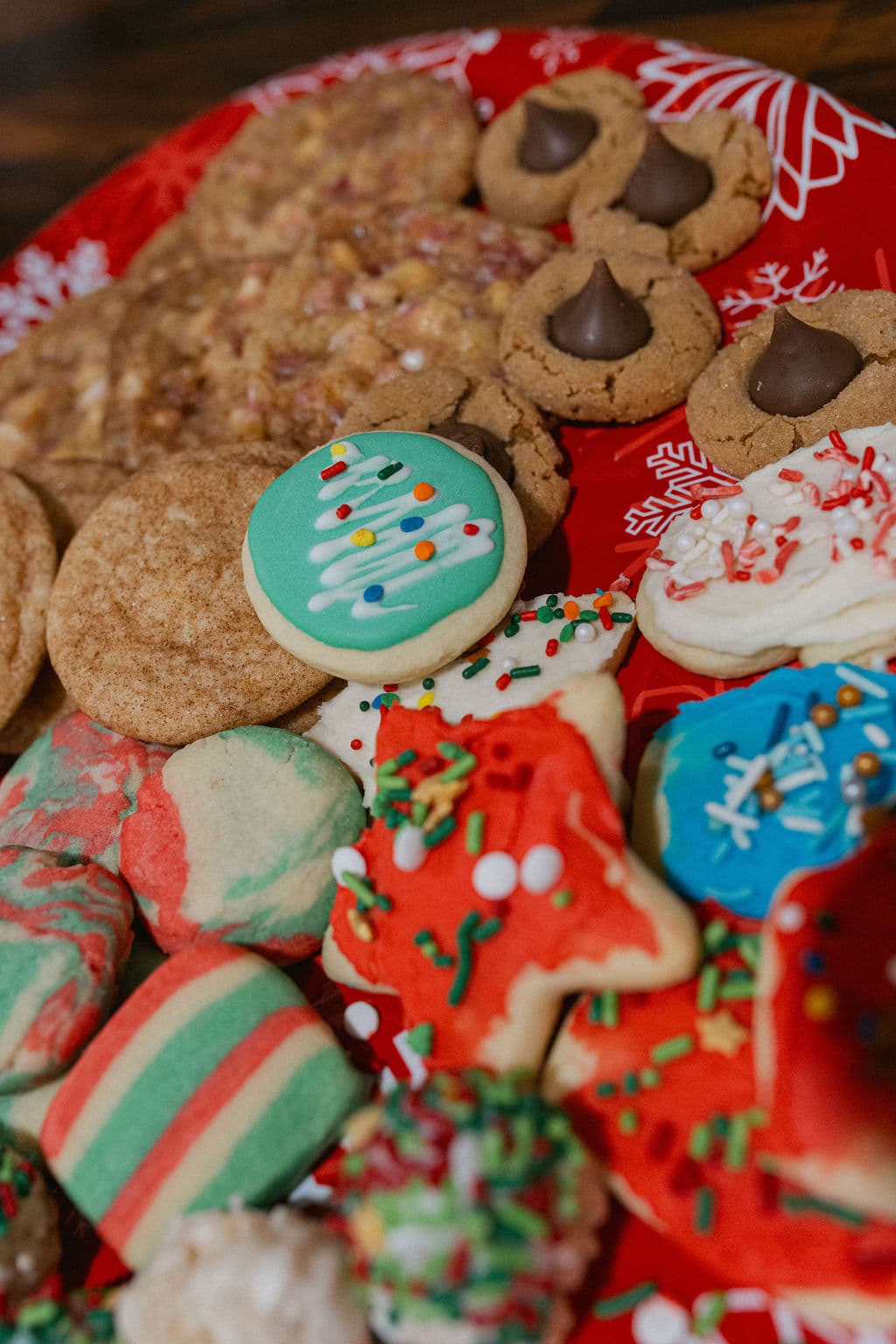 A colorful assortment of decorated holiday cookies on a festive red plate.