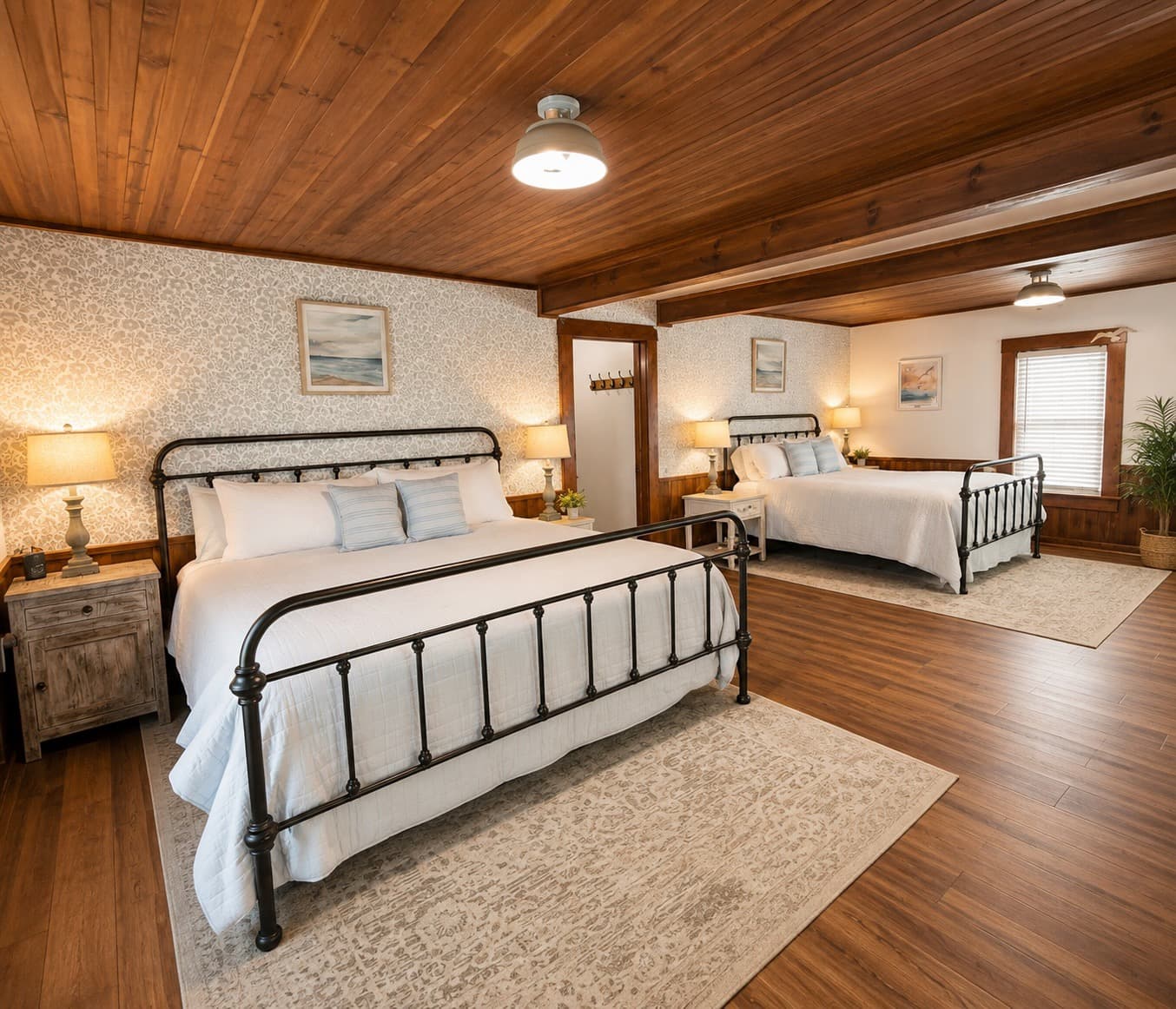 A cozy guest room featuring two metal framed beds, warm wooden accents, and soft lighting.